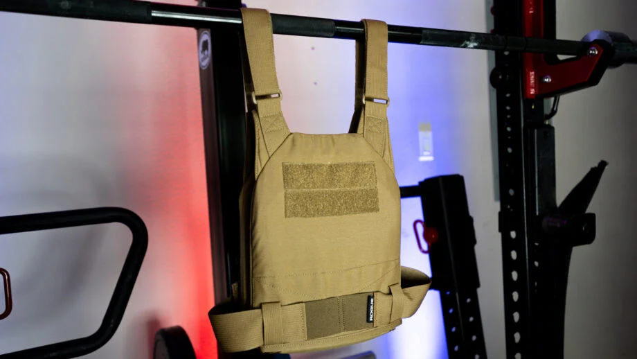 Side view of the Rogue Plate Carrier vest as it hangs from a barbell