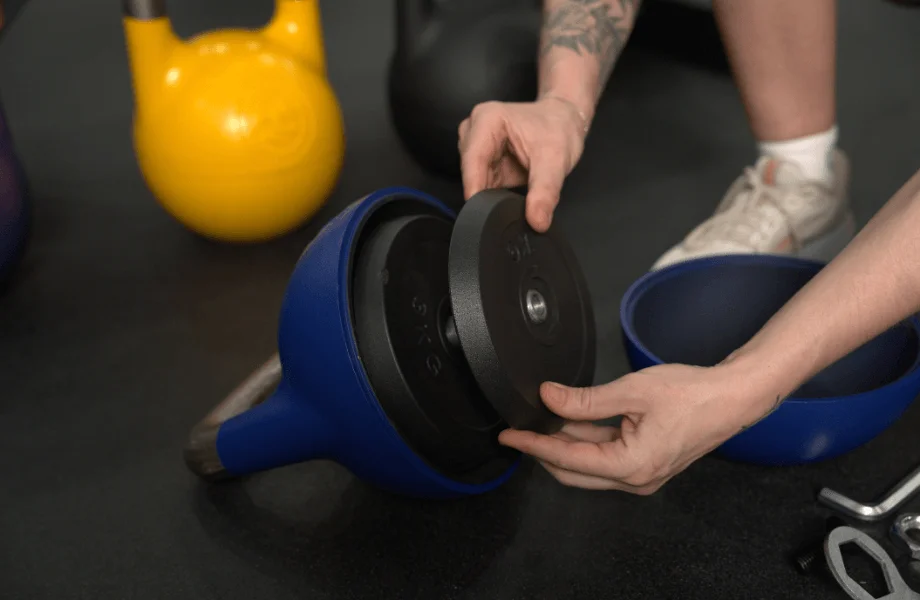 Our tester setting their working weight for a kettlebell workout with the Bells of Steel Adjustable Competition Style Kettlebell