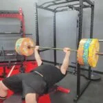 Olympian Caine Wilkes bench pressing with the Giant Lifting Garage Gym Power 2.0 Rack as a spotter