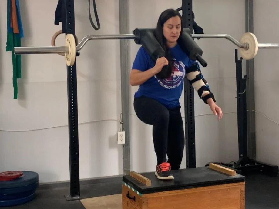 An injured woman uses the Titan Fitness Safety Squat Bar to perform step-ups