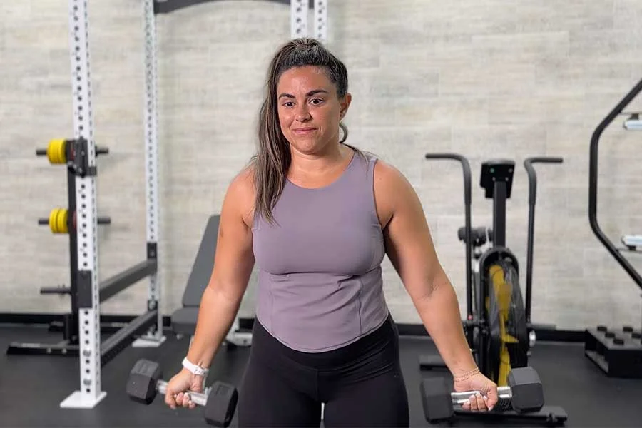 woman standing upright holding dumbbells