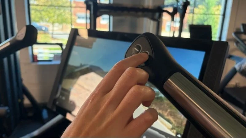 Our tester showing the easy-to-use adjustment buttons located on the Aviron Summit Treadmill's ergonomic handles.