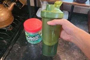 someone holding a shaker bottle with ghost greens