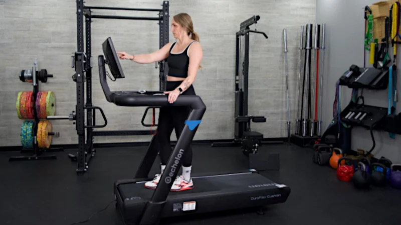 Woman standing on Echelon Stride 8s choosing programming