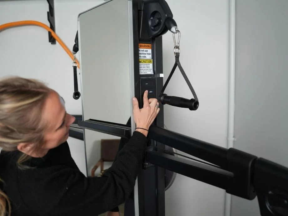 Pressing a button on the side of a NordicTrack Fusion CST machine.