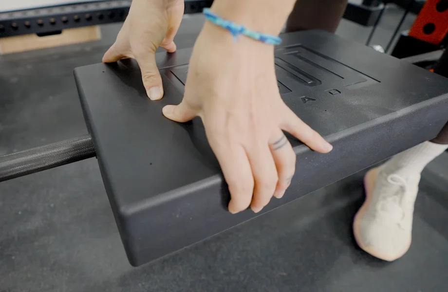 Lindsay Scheele, CPT grips an AbMat Pivot Pad to clip it onto a barbell.