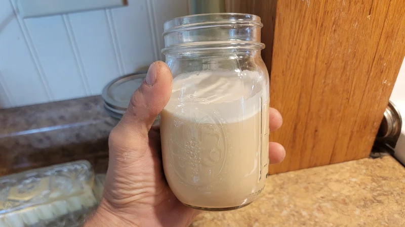 Our product tester holds up a TumLove Gut-Friendly Protein Powder shake in a pint-sized mason jar