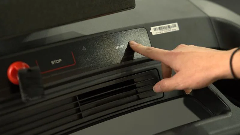 A hand reaches out to use the control panel on a NordicTrack Commercial 1250 treadmill.