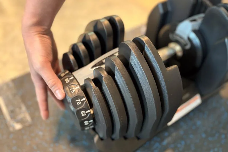 Our product tester turning the dial of the Bowflex Results Series 1090 SelectTech Adjustable Dumbbells