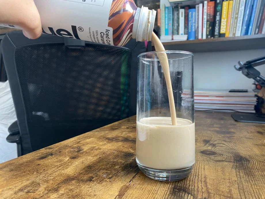 Pouring a bottle of Huel Ready-To-Drink into a glass