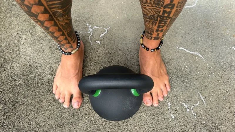 Looking down at an Iron Bull Strength Kettlebell between our tester's feet