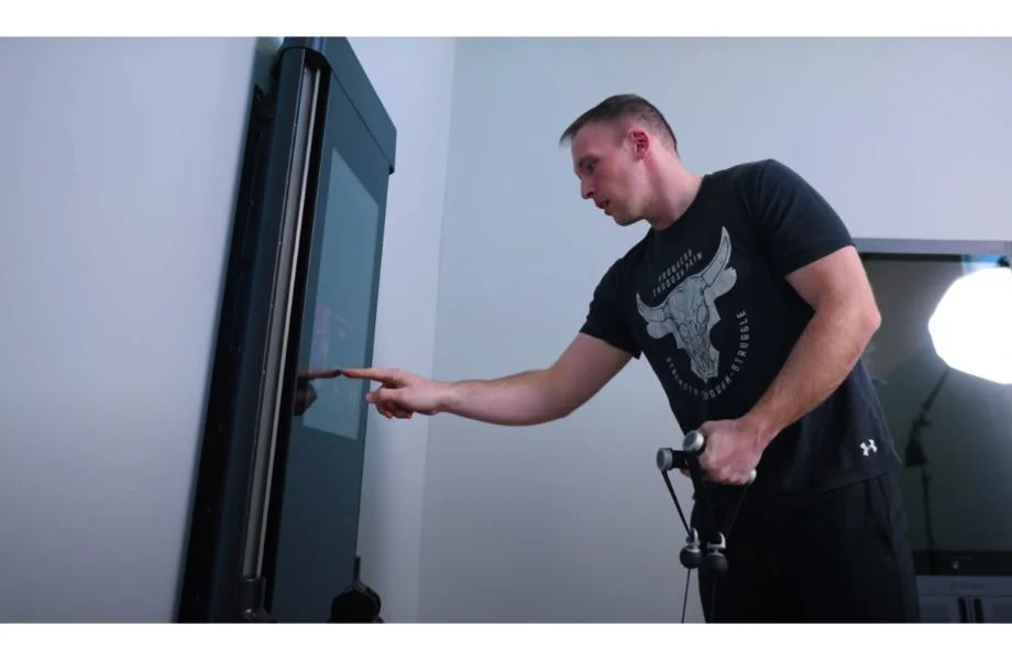Anthony using the touchscreen of a Tonal 2 Smart Home Gym Machine