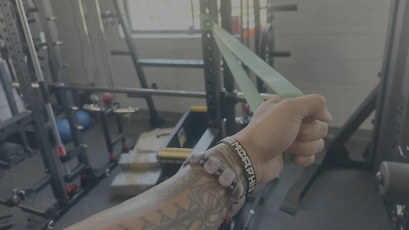 A hand pulls on a Rogue Monster Band that's attached to a rack