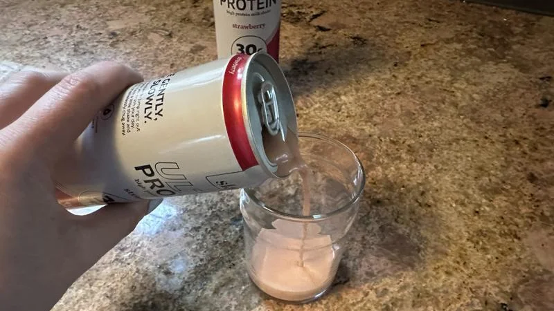 A hand pouring a glass of Slate Protein Powder