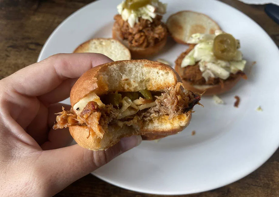 An image of a person's hand holding pulled pork sliders from Sunbasket