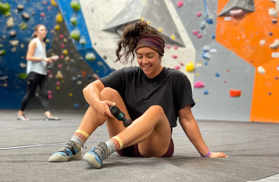 A person uses the Ekrin Bantam mini-massage gun on their calf muscles.