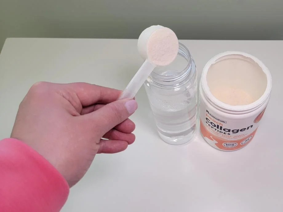 A hand pours a scoop of NativePach Collagen into a bottle filled with water
