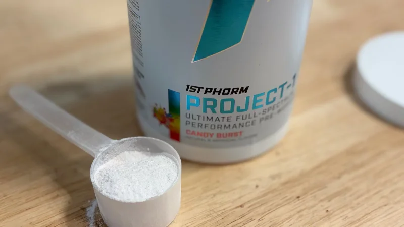 A scoop of 1st Phorm Project 1 Pre-Workout next to the opened container