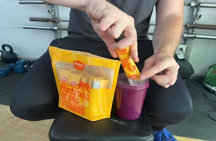 Our tester adding a single-serving packet of BUBS Naturals Hydrate or Die electrolytes to their shaker bottle