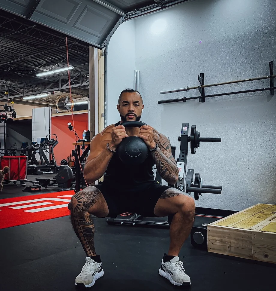 Man performs goblet squat with a kettlebell.