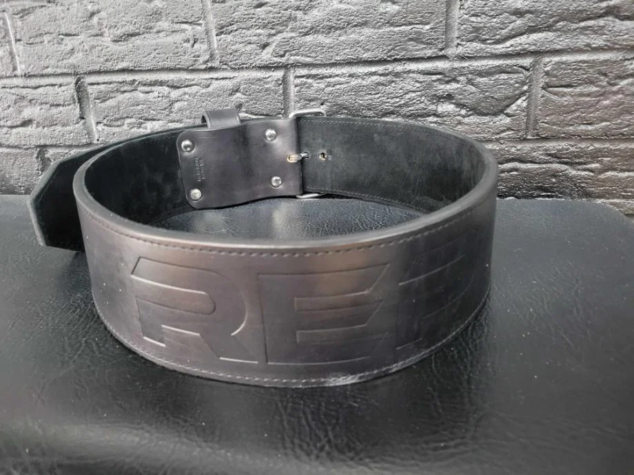 The REP USA Premium Leather Lifting Belt seated on a weight bench