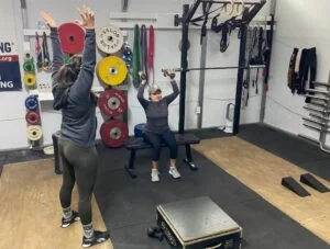 personal trainer instructing seated shoulder press
