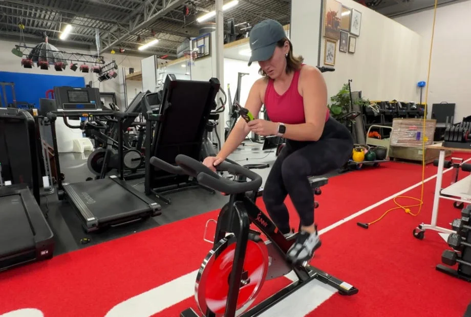 A person takes a decibal reading while riding the Sunny B1002 Foldable Exercise Bike