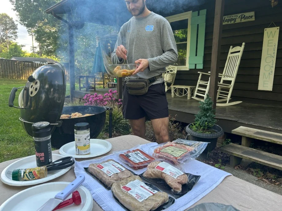 A person is grilling a lot of meat from the Carnivore Club.