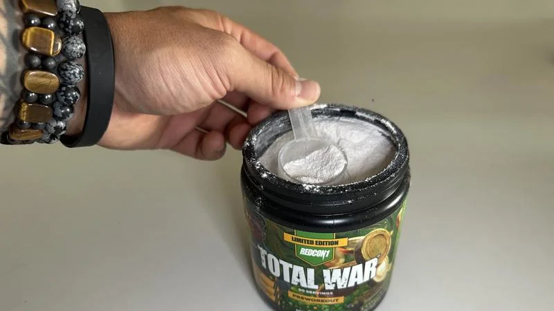 A hand scooping Redcon1 Total War Pre-Workout
