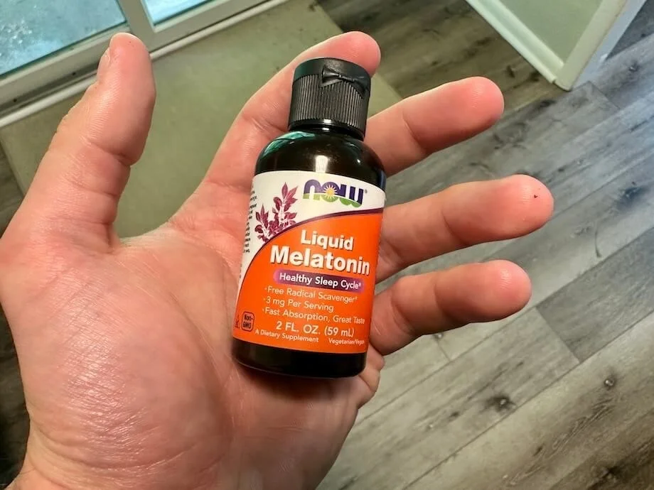A person holds a bottle of NOW Liquid Melatonin.