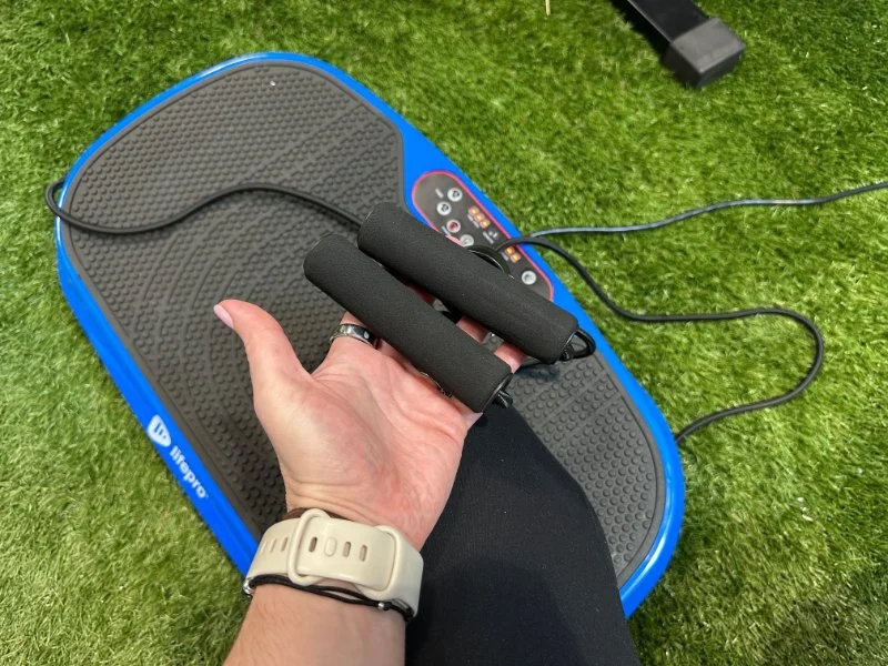 A person holds up the handles on a MERACH LifePro Waver Mini vibration plate