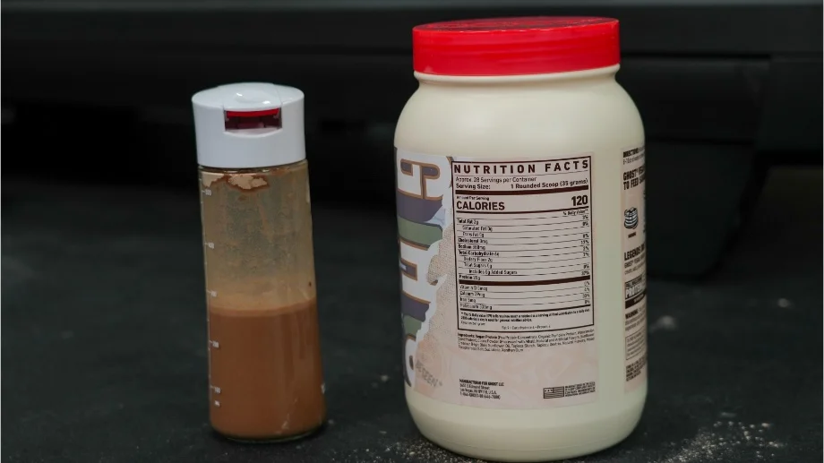 A shaker glass of Ghost Vegan Protein next to the Nutrition Facts label on the container.