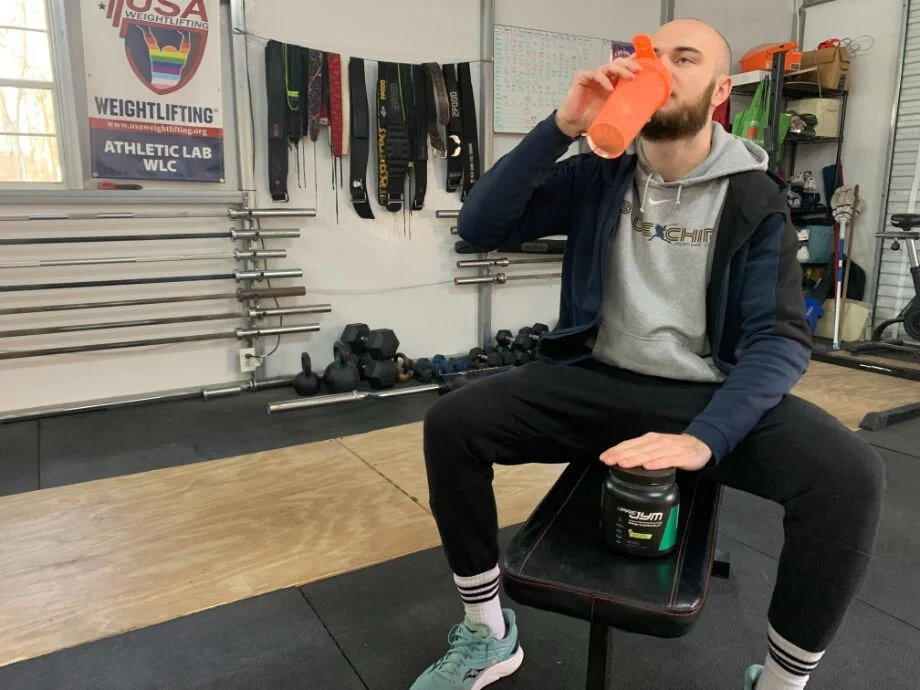 A man drinks a JYM Supplement Pre-Workout from his shaker bottle
