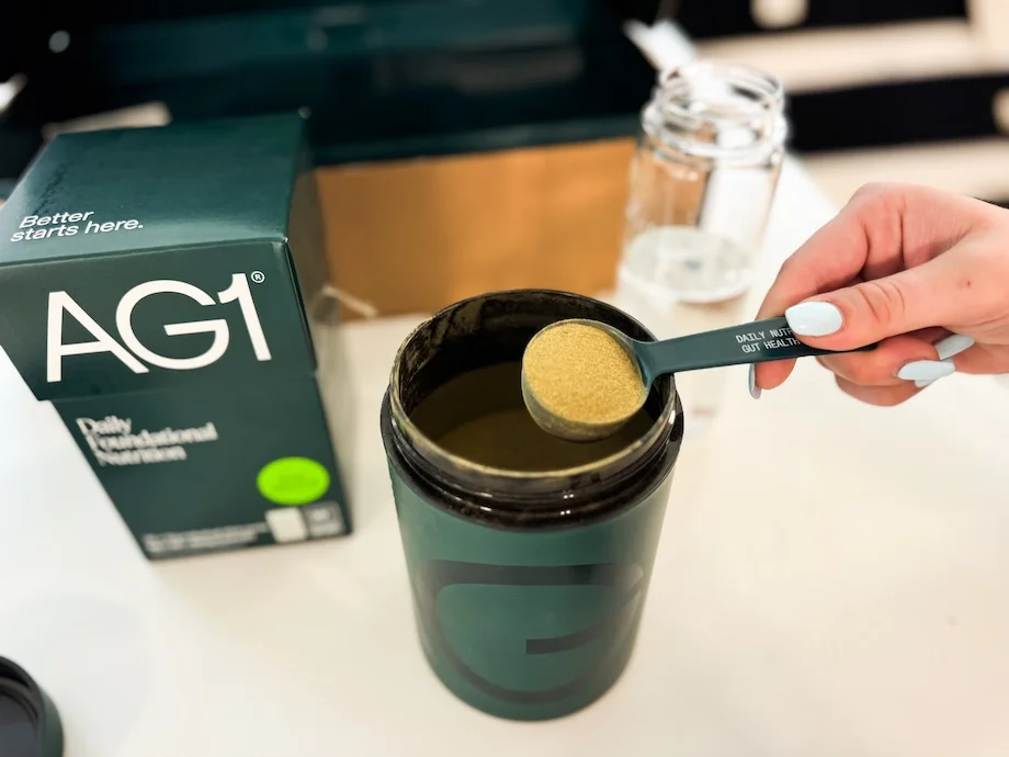 Woman scooping a serving of AG1 supplement