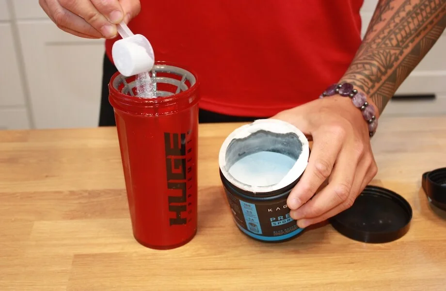 Our tester adding a scoop of Kaged Pre-Workout Sport to their shaker bottle