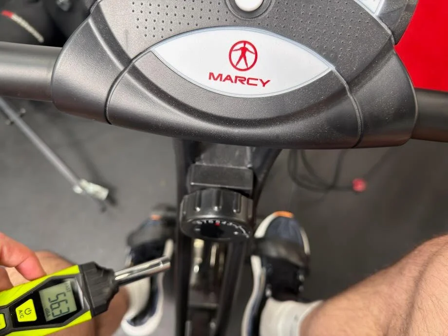 A person uses a decibal testing device while using the Marcy Foldable Upright Bike