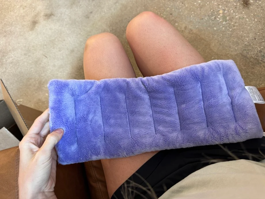 A person holds a Suzzipad Microwaveable Heating Pad in their lap