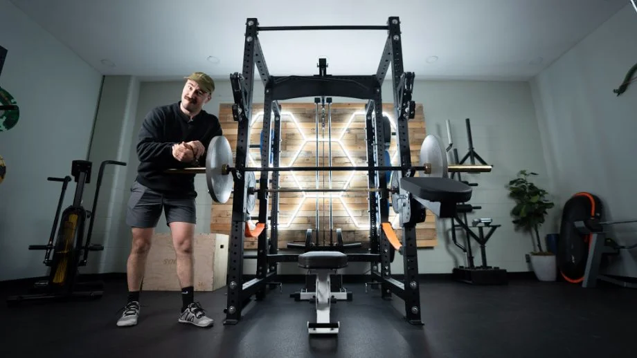 Coop standing in a home gym next to a Bells of Steel Hydra Rack