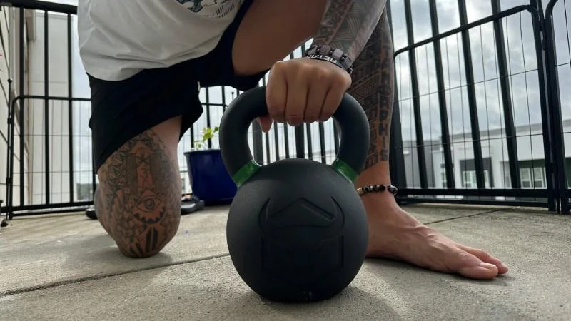 Our tester kneeling with the Iron Bull Strength Kettlebell.