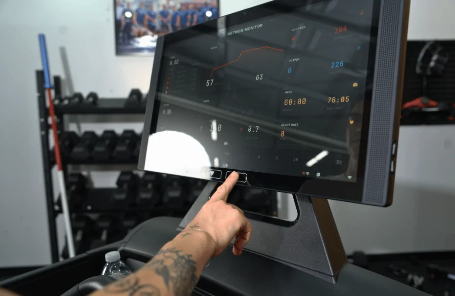Our tester navigating through specs on the Aviron Victory Treadmill's 22-inch HD touchscreen