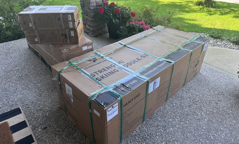An image of the FitTransformer Titan in boxes on a porch