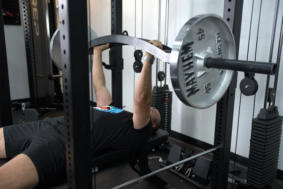 Coop performs bench press with a cambered Swiss bar on the Body-Solid Functional Trainer Rack