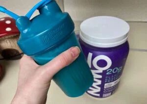 owyn plant protein holding shaker cup in front of bottle