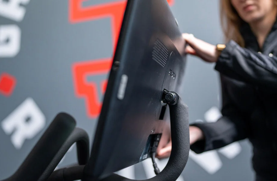 A person adjusting a Peloton bike screen.