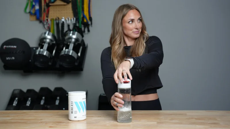 Woman using Swolverine BCAA powder.