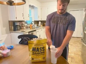 COVER IMAGE man putting crazy nutrition mass gainer into cup