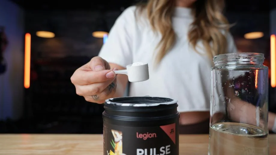 A woman holds a scoop of Legion Pulse
