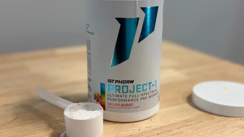 A scoop of 1st Phorm Project 1 Pre-Workout next to the opened container