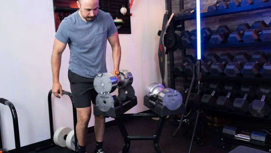 Man picking up one Trulap adjustable dumbbell