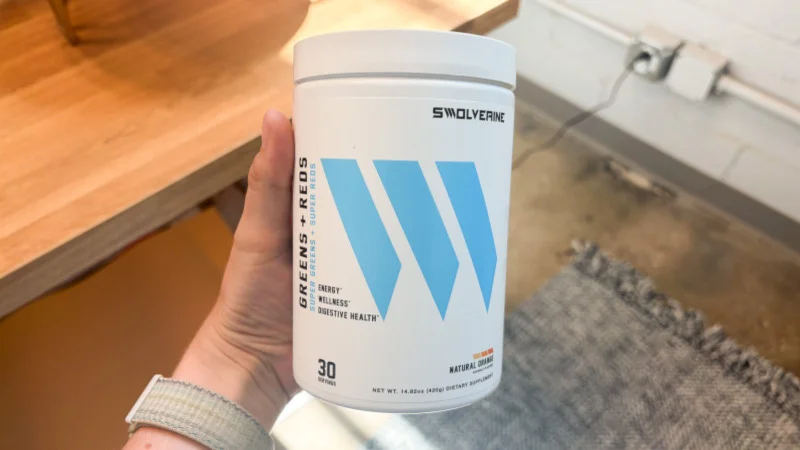A person holding Swolverine Greens + Reds powder